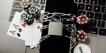 Law and rules for online casino concept, smartphone with padlock and playing chips on keyboard