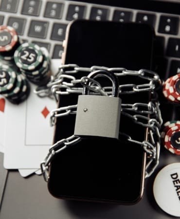 Law and rules for online casino concept, smartphone with padlock and playing chips on keyboard